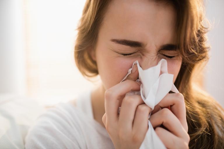 Lady sneezing into tissue