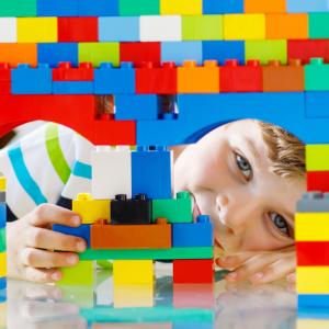 Boy peeking through a tower of building bricks