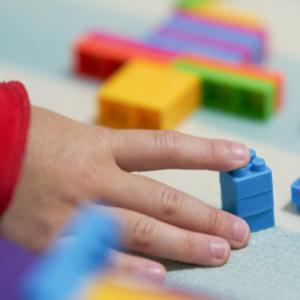 Child's hand playing with Lego bricks